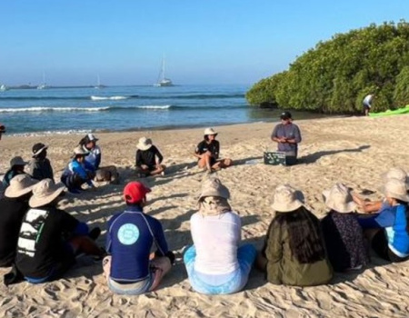 Niños participantes del proyecto Naveducando, sentados en formación circular en la arena de la playa